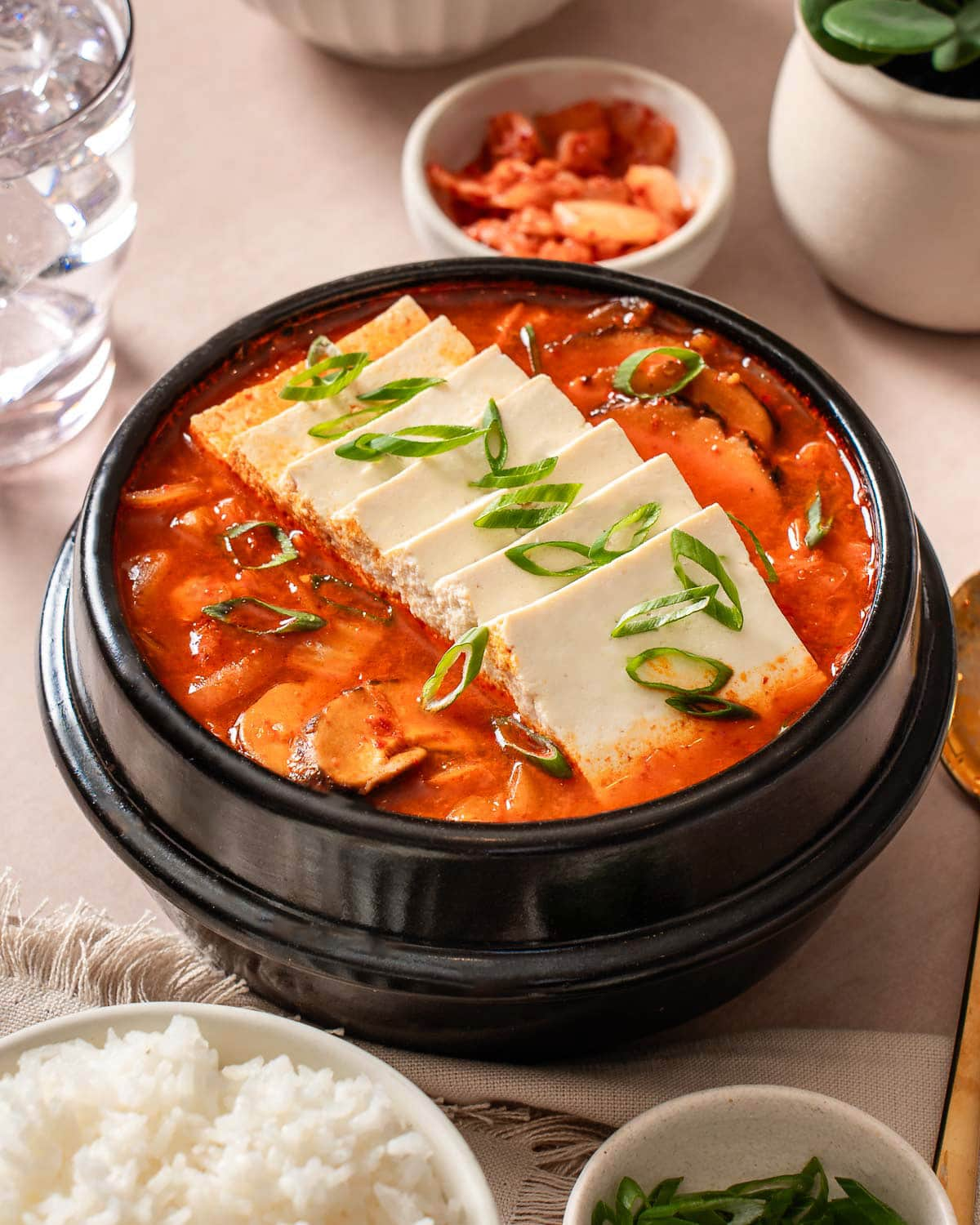 Kimchi-jjigae in a stone bowl with side dishes